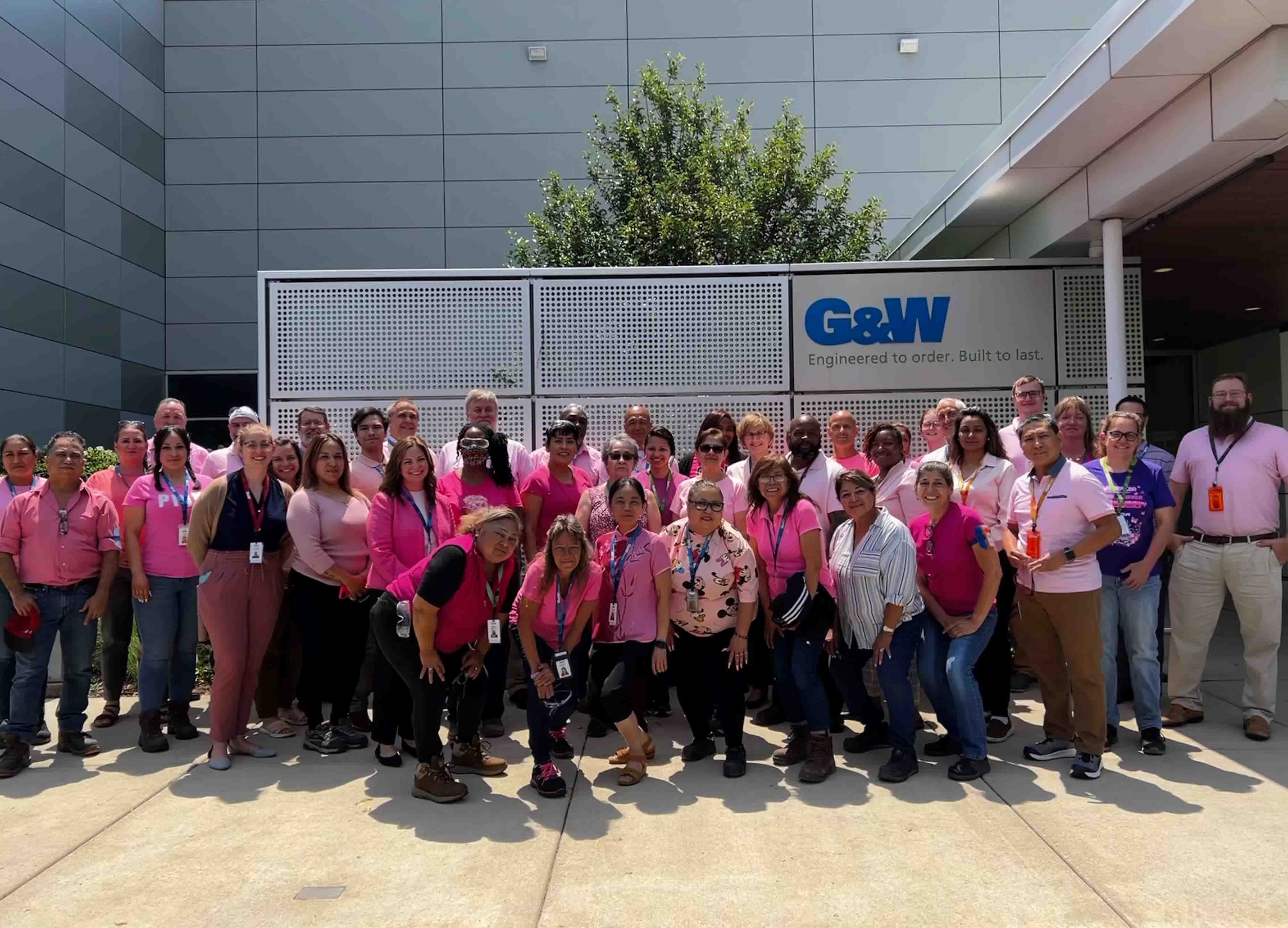 Group photo all wearing pink in front of G&W building